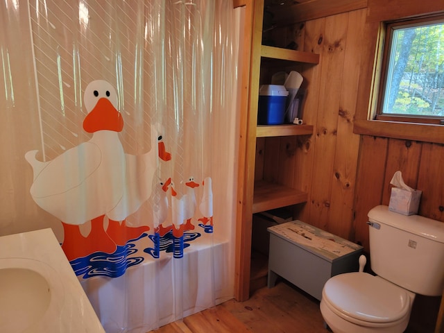 bathroom with shower / bath combo with shower curtain, toilet, and wood walls