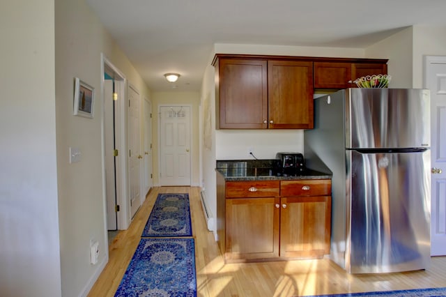 kitchen with dark stone countertops, light hardwood / wood-style flooring, and stainless steel fridge