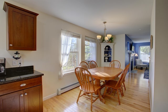 dining space featuring an inviting chandelier, a baseboard heating unit, and light hardwood / wood-style floors