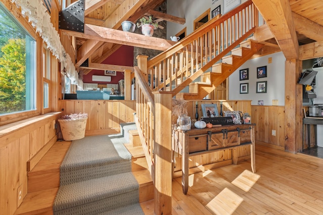 stairs with hardwood / wood-style floors, wood walls, and lofted ceiling with beams