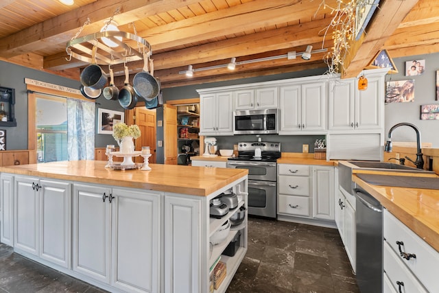 kitchen with white cabinetry, butcher block counters, and appliances with stainless steel finishes