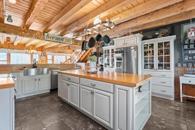 kitchen with stainless steel appliances, white cabinetry, and wooden counters