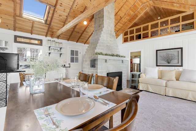 dining area with wooden ceiling, high vaulted ceiling, a stone fireplace, a skylight, and beam ceiling