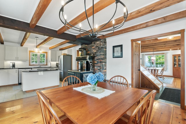 dining area featuring beam ceiling, sink, a chandelier, and light hardwood / wood-style flooring