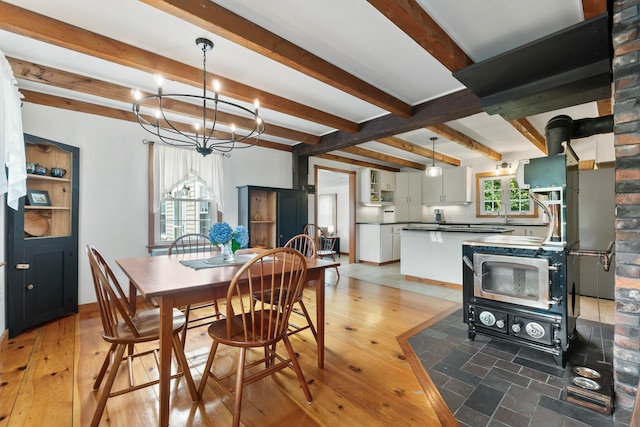 dining area featuring beamed ceiling, a notable chandelier, and wood-type flooring