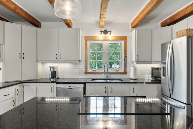 kitchen featuring stainless steel appliances, sink, dark stone counters, white cabinetry, and beam ceiling