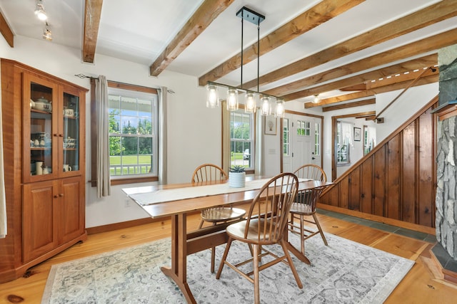 dining space featuring light wood-type flooring and beam ceiling