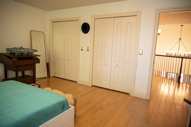 bedroom featuring light hardwood / wood-style flooring, two closets, and a chandelier