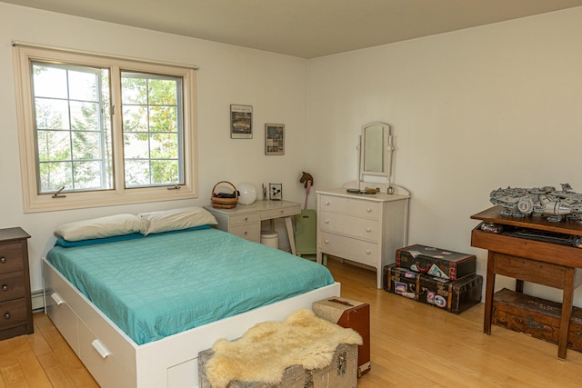 bedroom featuring a baseboard heating unit and light wood-type flooring