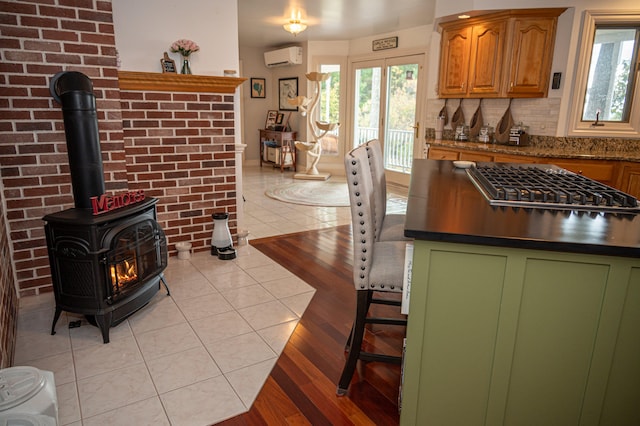 kitchen featuring plenty of natural light, light tile patterned floors, a wood stove, and a wall mounted AC