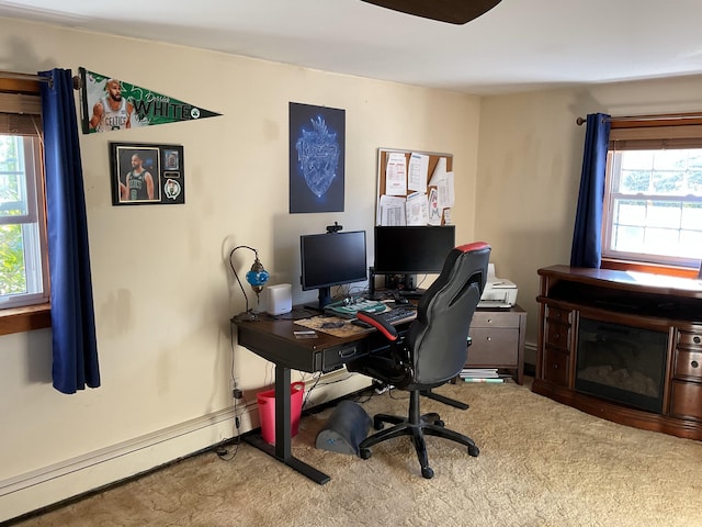 carpeted office with a baseboard heating unit and a healthy amount of sunlight