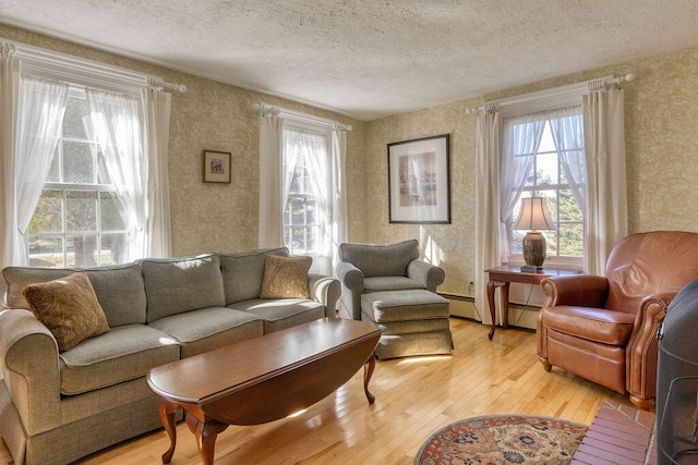 living room featuring light hardwood / wood-style floors, a textured ceiling, and a baseboard heating unit