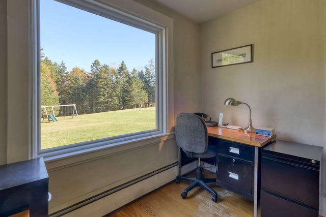 home office with light hardwood / wood-style floors, a healthy amount of sunlight, and baseboard heating