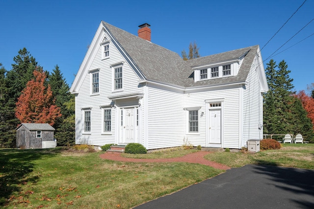 view of front of house featuring a front yard and a storage shed