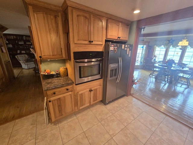 kitchen with appliances with stainless steel finishes, light wood-type flooring, and dark stone countertops