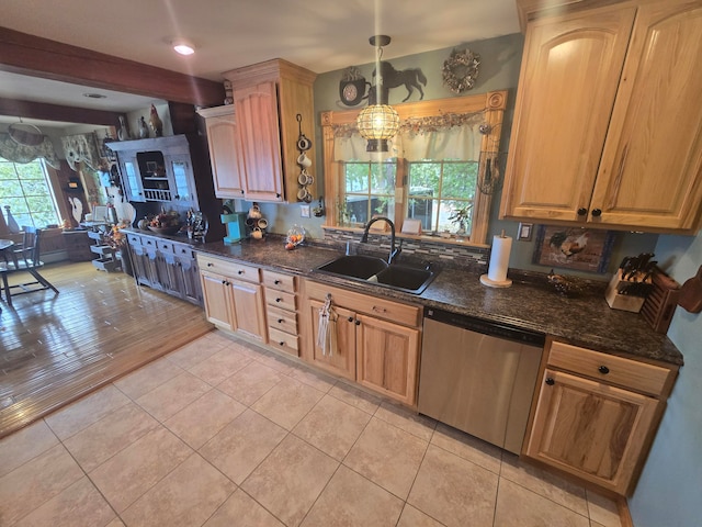 kitchen featuring dark stone countertops, sink, decorative light fixtures, light tile patterned floors, and stainless steel dishwasher