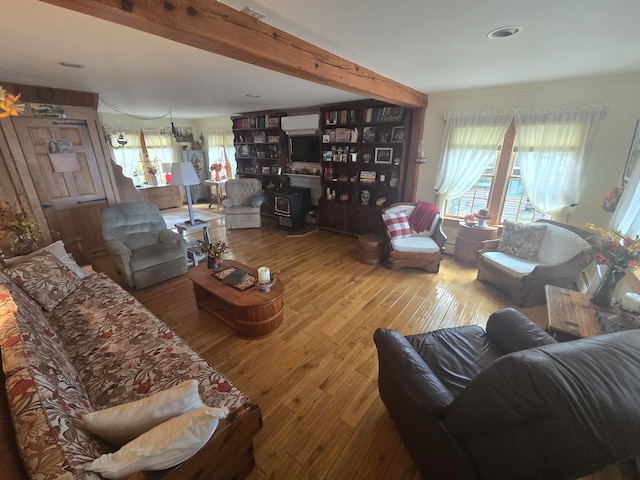 living room with beamed ceiling, a wood stove, an AC wall unit, and wood-type flooring