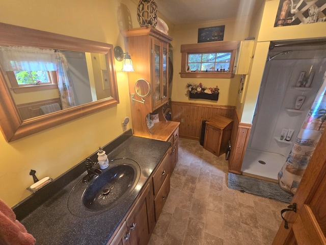 bathroom with vanity, curtained shower, wood walls, and a healthy amount of sunlight