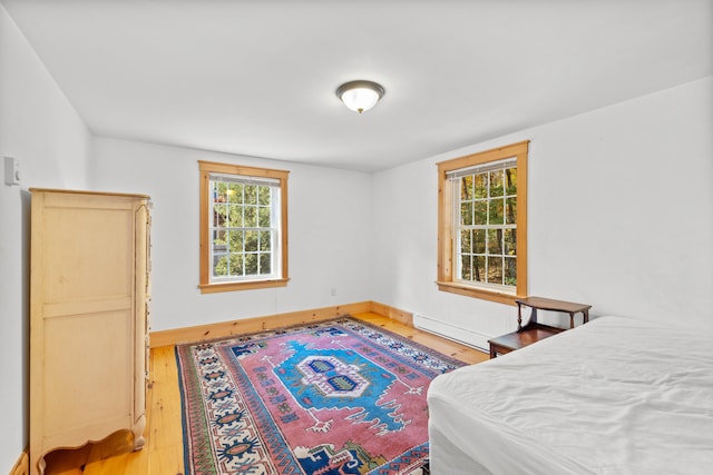 bedroom with hardwood / wood-style floors and baseboard heating