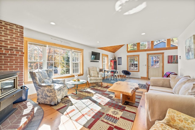 living room with vaulted ceiling, light hardwood / wood-style flooring, and a brick fireplace