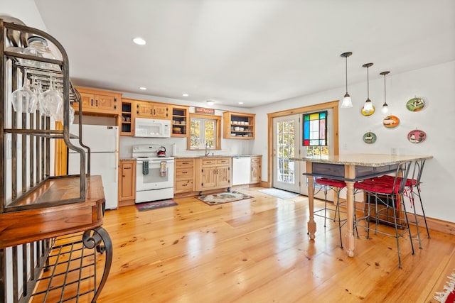 kitchen featuring light brown cabinets, a breakfast bar area, light hardwood / wood-style floors, sink, and white appliances