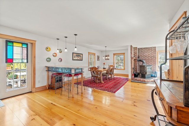 dining area with an inviting chandelier, hardwood / wood-style floors, and a wood stove