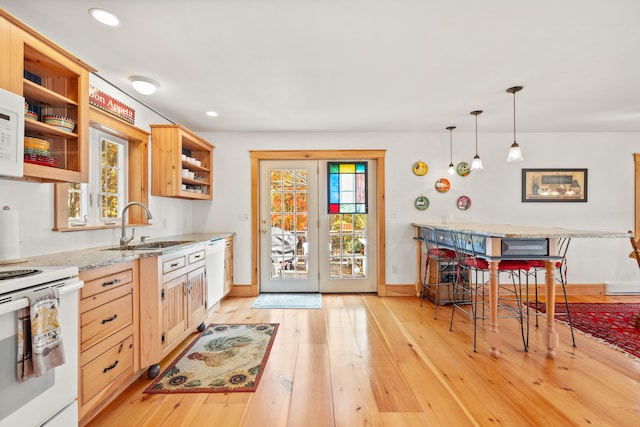 kitchen with light brown cabinetry, light hardwood / wood-style flooring, pendant lighting, sink, and white appliances