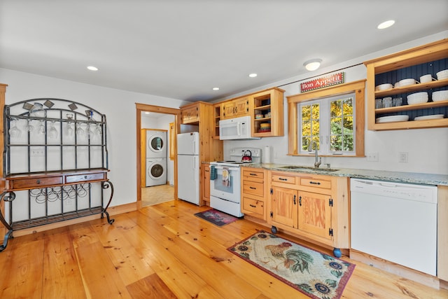 kitchen with white appliances, light stone countertops, sink, light hardwood / wood-style floors, and stacked washer / drying machine