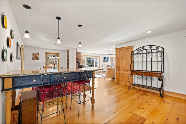 kitchen with stone counters, hanging light fixtures, and light wood-type flooring