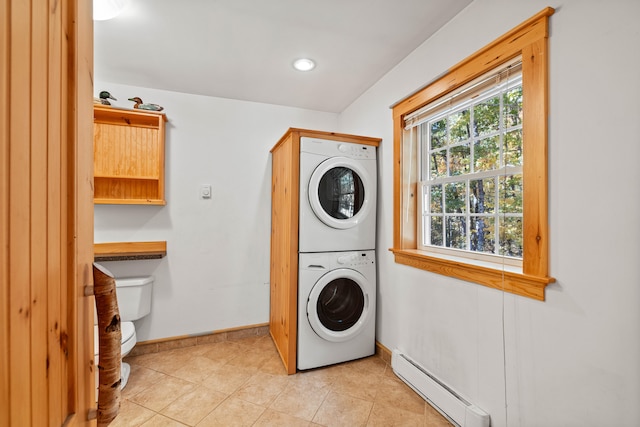 laundry area with light tile patterned flooring, a baseboard radiator, and stacked washer and dryer