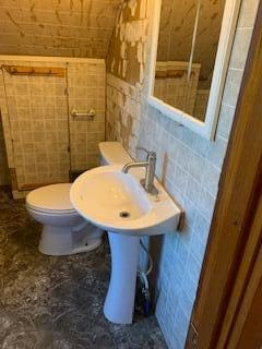 bathroom featuring toilet and tile walls