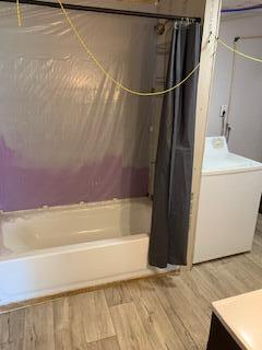 bathroom featuring washer / dryer, shower / bath combination with curtain, vanity, and wood-type flooring