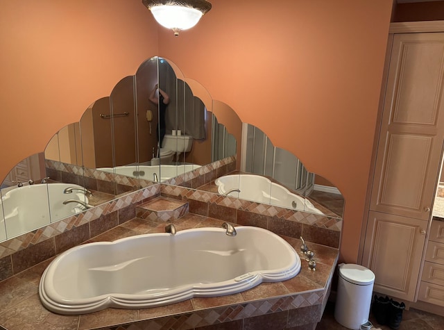 bathroom featuring toilet and tiled tub