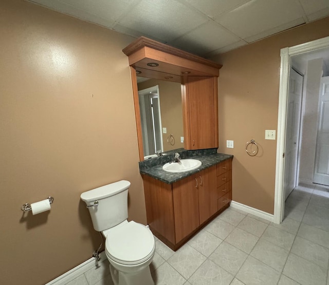 bathroom featuring vanity, a drop ceiling, toilet, and tile patterned flooring