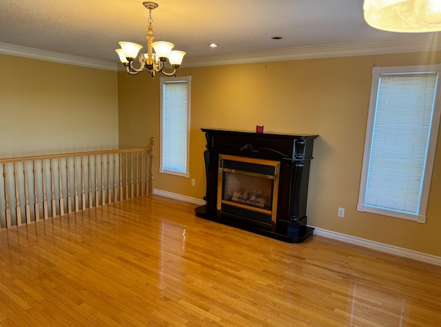 unfurnished living room featuring light hardwood / wood-style floors, crown molding, a textured ceiling, and a chandelier