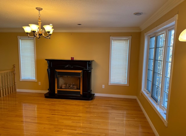 interior space featuring crown molding, light hardwood / wood-style flooring, a textured ceiling, and an inviting chandelier