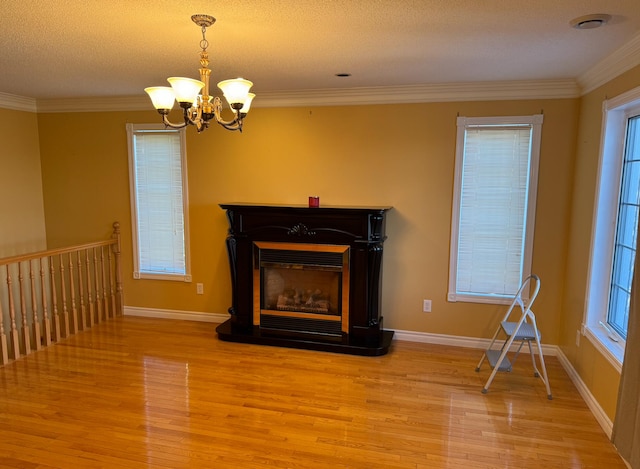 unfurnished living room with ornamental molding, light hardwood / wood-style flooring, a textured ceiling, and a healthy amount of sunlight