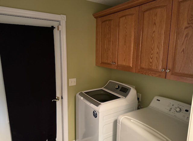 clothes washing area with washing machine and dryer and cabinets