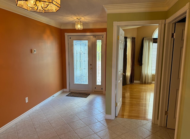 entrance foyer with a notable chandelier, ornamental molding, and light tile patterned flooring