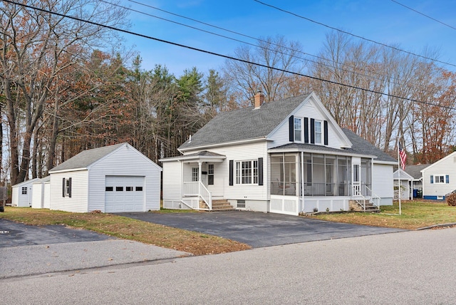 view of front of home featuring a garage, a sunroom, and an outdoor structure