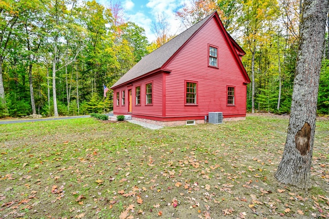 view of side of property featuring a lawn and central AC