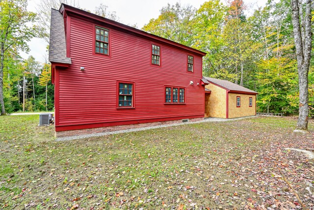 view of side of home featuring cooling unit and a yard