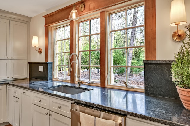 kitchen featuring stainless steel dishwasher, white cabinets, sink, and pendant lighting