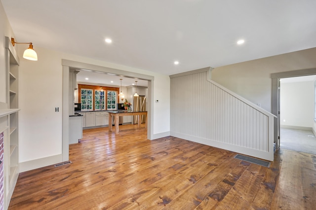 unfurnished living room with light hardwood / wood-style floors and built in shelves