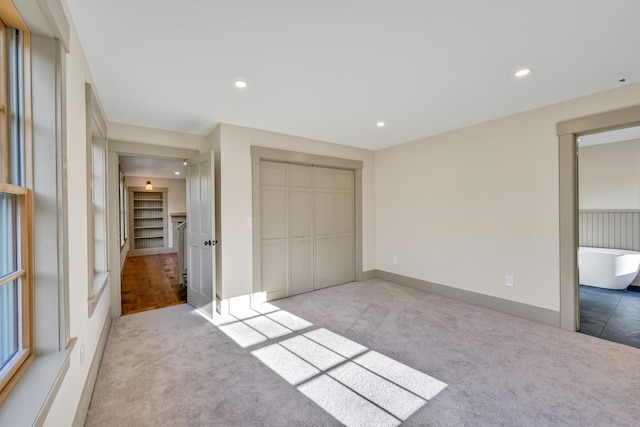 unfurnished bedroom featuring light colored carpet and a closet