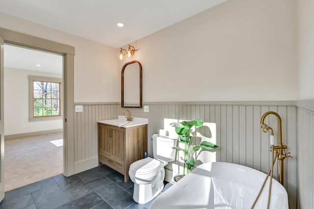 bathroom with toilet, a washtub, and vanity