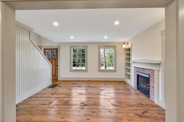 unfurnished living room with a brick fireplace and hardwood / wood-style floors