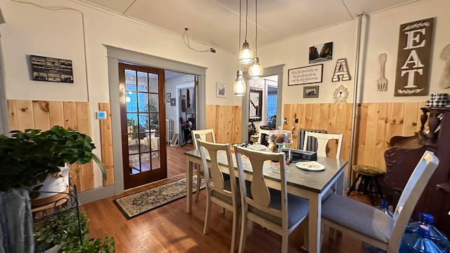 dining space with french doors, wood walls, and hardwood / wood-style floors