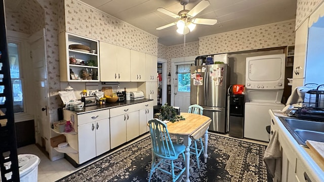 kitchen featuring white cabinets, stacked washer / dryer, wood counters, and stainless steel fridge