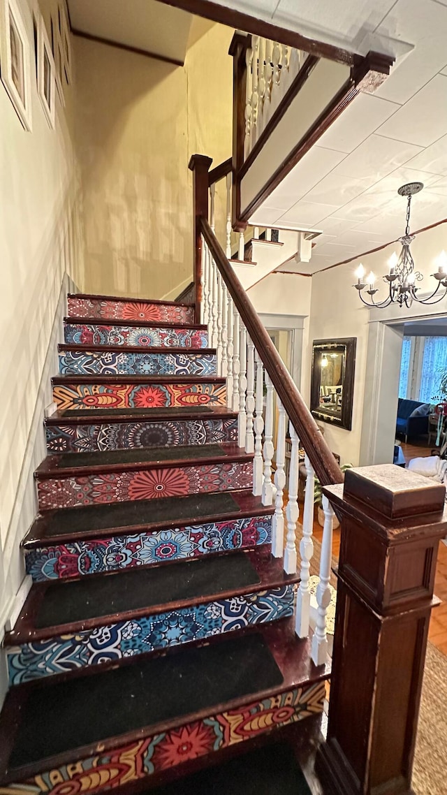 stairs featuring a chandelier